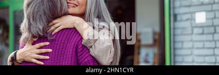 Senior Asian woman hugs friend meeting on modern city street Stock Photo