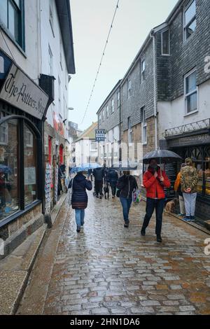 St Ives, UK - February 2022: Shoppers at St Ives Fore Street on a rainy day Stock Photo