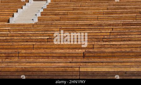 Rows of empty wooden benches in open air city public event space. Modern urban public vandal proof resting furniture.  Stock Photo