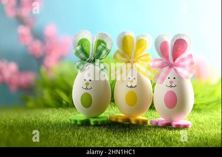 Easter eggs in grass against blurred blue blooming flower background. Spring holidays concept. Stock Photo