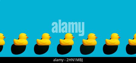 Yellow rubber ducks arranged in a row on blue background. Stock Photo