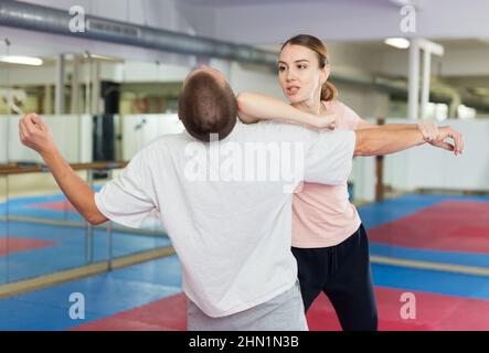 Active girl conducts painful grip on self-defense training in gym Stock Photo