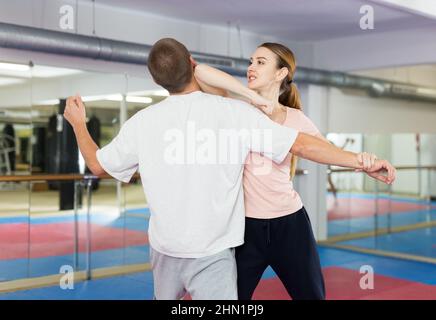 Active girl conducts painful grip on self-defense training in gym Stock Photo