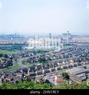 A view of the Port Talbot Steelworks, an integrated steel production plant in Port Talbot, West Glamorgan, Wales, UK c. 1980. The main access road at this time was Cefn Gwrgan Road, here running from the bottom left over a railway bridge to the works. This access road was cut by the building of Harbour Way bypass in 2013. This image is from a vintage colour transparency – a vintage 1970s/80s photograph. Stock Photo