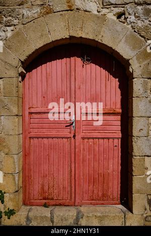 Red wooden door inside of stone wall Stock Photo