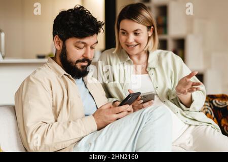 White couple using cellphones while sitting on couch at home Stock Photo