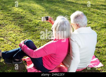 Elderly people living their life at its best. Couple of retired people taking selfies with outdoor light Stock Photo