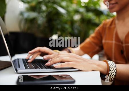Hands of young biracial woman typing on laptop keyboard while searching for new equipment for orangerie or seeds of flowers in the net Stock Photo