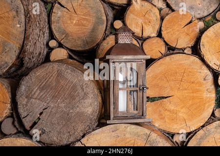 An old portable lantern stands in a rustic wood-burning room. There is a door on the lantern to replace the candle. Composition in retro style Stock Photo