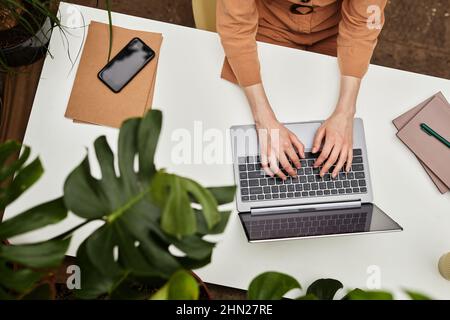 Overview of hands of young businesswoman or student typing on laptop keyboard by desk while working over presentation Stock Photo