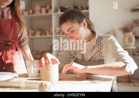 Beautiful young woman making coffee mug at ceramics class Stock Photo