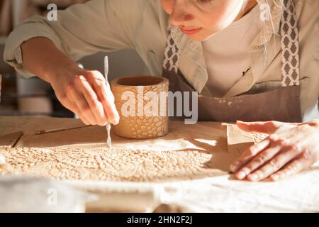 Cropped close up of a woman making ceramic coffee mug, working in sunlight Stock Photo