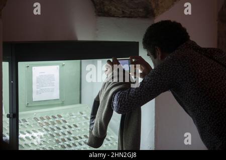 Visitor taking pictures to ancient coins glass cabinet. Osuna Archaeological Museum, Seville Stock Photo