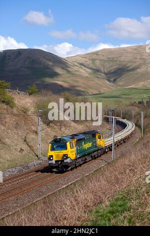 Freightliner class 70 diesel locomotive in the Cumbrian countryside on the west coast mainline with freight train carrying materials for Network Rail Stock Photo