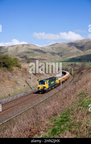 Freightliner class 70 diesel locomotive in the Cumbrian countryside on the west coast mainline with freight train carrying materials for Network Rail Stock Photo