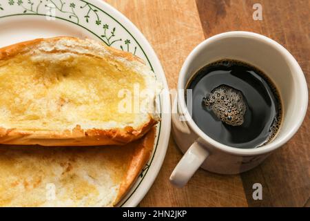 Goiânia, Goias, Brazil – February 13, 2022: Two buns on the plate and a cup of coffee on a wooden surface. Stock Photo