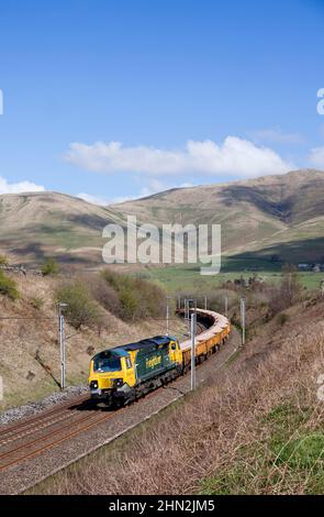 Freightliner class 70 diesel locomotive in the Cumbrian countryside on the west coast mainline with freight train carrying materials for Network Rail Stock Photo