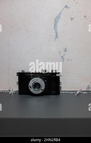 Old vintage plastic black analog photography camera as a decoration object on a grey shelf Stock Photo