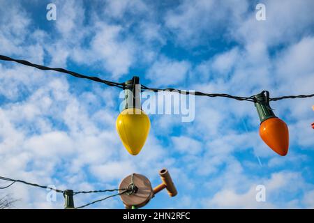 Colorful light bulbs as a decoration item on a blue cloudy sky on a party Stock Photo