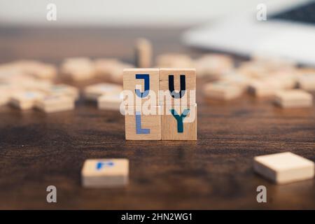 The name of the month July written on wooden cubes od the tabletop of th computer desk. High quality photo Stock Photo