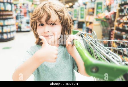 Portrait of child in grocery shopping in supermarket, Boy with a grocery cart. Stock Photo