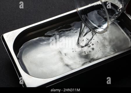 silver metal tray with water highlighted on a black background Stock Photo