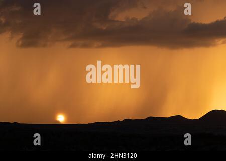 The sun sets behind a veil of rain during the summer monsoon season in the Chihuahuan Desert, Texas. Stock Photo