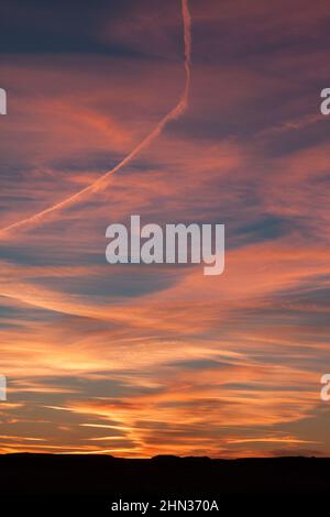 Brilliant sunset with cirrus clouds and contrails near Green River, Utah Stock Photo