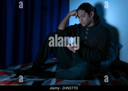 Insomnia, Depressed man sitting up in bed at night, he can't sleep from insomnia Stock Photo