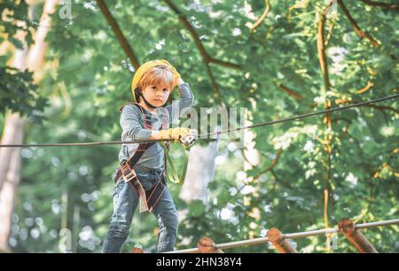 Cute child boy playing. Artworks depict games at eco resort which includes flying fox or spider net. Every childhood matters. Toddler age. Children Stock Photo