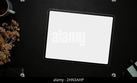 Digital tablet mockup for displaying your graphic on a white screen over a black table background with dried flowers and accessories. top view, flat l Stock Photo