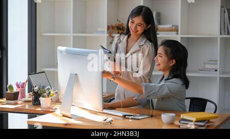 Cheerful businesswomen, business colleague are enjoying working together in the office. brainstorming, having a great conversation. Stock Photo