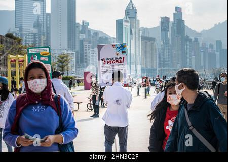 Hong Kong, China. 12th Feb, 2022. Staff member from the Hong Kong Labour Department hands out leaflets and reminds residents about COVID-19 social distancing rules. With a recent increase in cases in Hong Kong, the government has increased testing and furthered limits on social gatherings in an effort to combat the disease. Credit: SOPA Images Limited/Alamy Live News Stock Photo