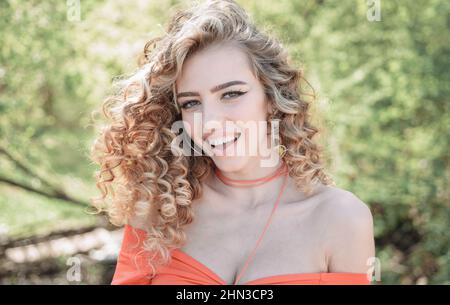 Beautiful Woman Enjoying Nature. Woman natural portrait. Beautiful skin woman with healthy curly hair and beauty eyes, lashes and red lips. Stock Photo