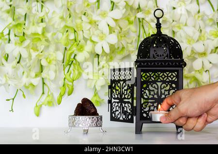 Candle puts in lantern with dates fruit that have orchid flower on white background for the Muslim feast of the holy month of Ramadan Kareem. Stock Photo