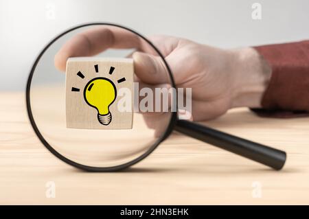 Magnifying glass with light bulb icon. Concept creative idea and innovation. Idea and imagination. Creative and inspiration. Magnifying glass and hand Stock Photo