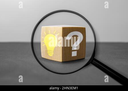 Idea, Analysis, Keyword, Content, seo, faq, Answer, and Information concept. Magnifying glass with question mark and lightbulb in focus on wooden cube Stock Photo