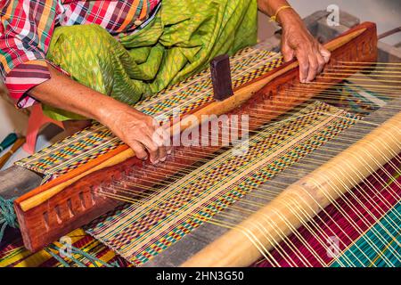 Closeup old woman hands weaving mats from dry reed. Stock Photo