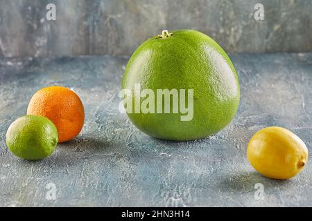 Pomelo red inside with tangerine and lemons lies on blue concrete. Stock Photo