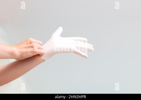 Woman doctor putting on medical latex surgical glove on white background Stock Photo