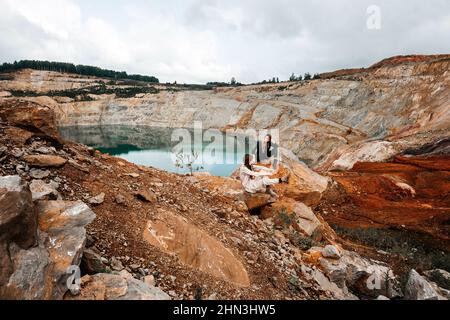 Girls in a post-apocalyptic place, a quarry with red earth and stones in work clothes Stock Photo