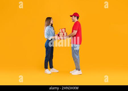 Courier Giving Gift Boxes To Customer Woman Over Yellow Background Stock Photo