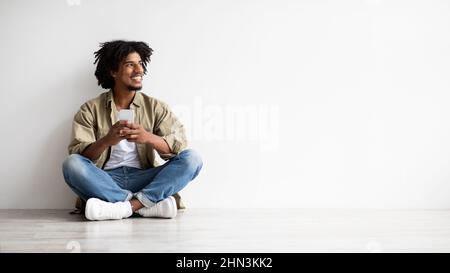 Online Offer. Smiling African American Guy Holding Smartphone And Looking Aside Stock Photo