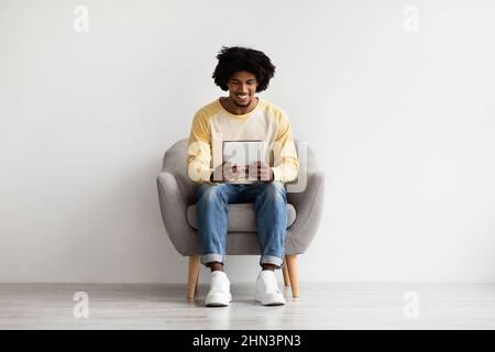 Happy Young African American Man Using Digital Tablet At Home Stock Photo