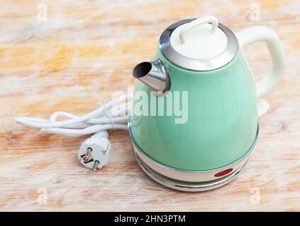 Metal light green electric kettle on wooden surface Stock Photo