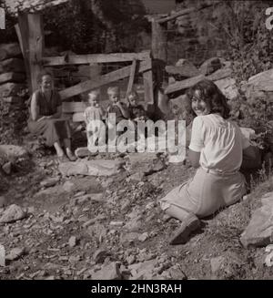Vintage photo of American life in 1940s. Marion Post  Wolcott photographing mountain children on stone steps of their home. Up Stinking Creek, Pine Mo Stock Photo