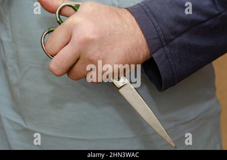 Old scissors in fist. Hand holds large sewing scissors. Close-up. Inside the room. Selective Focus. Stock Photo