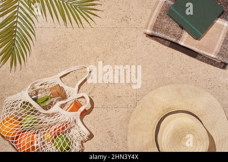Summer sun beach concept flat lay.Hat, string bag with fruits and lemonade Stock Photo
