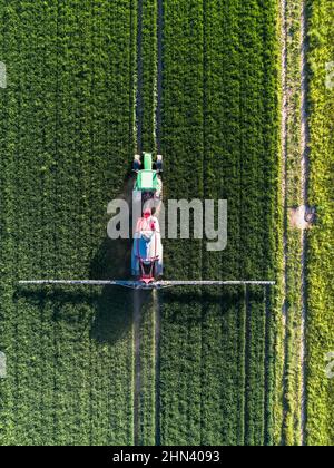 Aerial view tractor spraying lush green field, Baden-Wuerttemberg, Germany Stock Photo