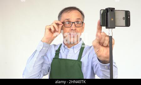 An elderly male blogger prepares to start broadcasting. Stock Photo